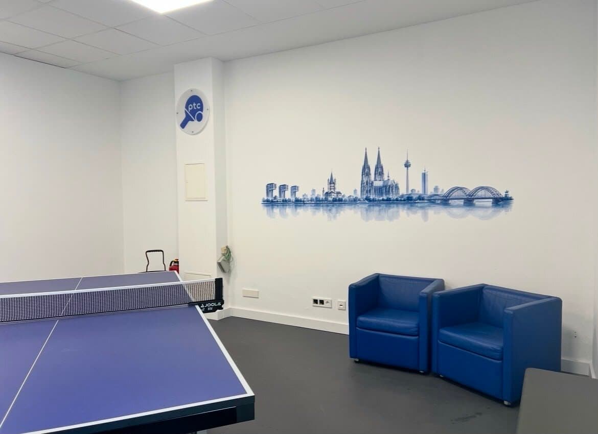 Lounge-Ecke mit blauen Sesseln unter dem Köln-Wandbild