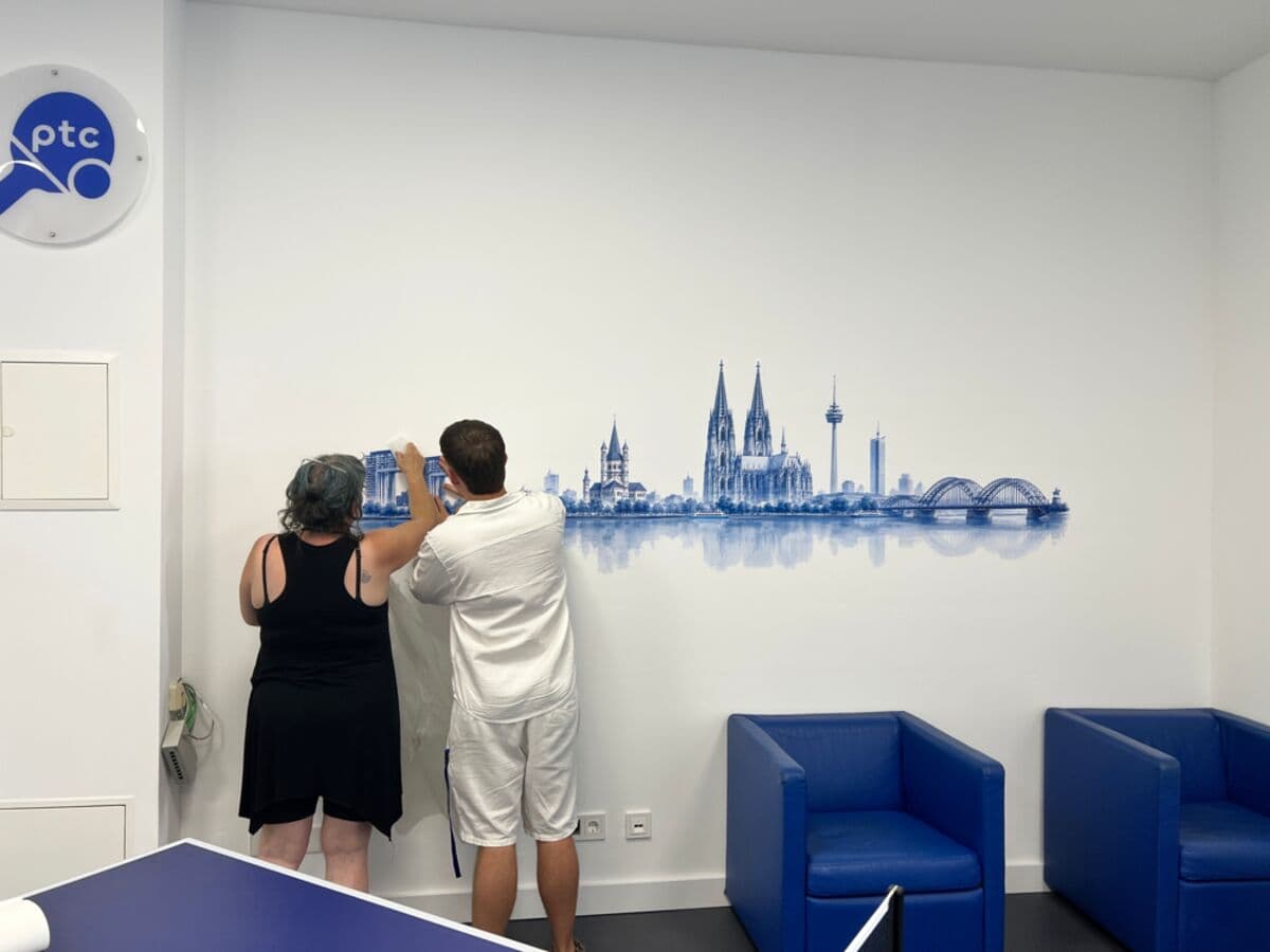Zwei Helfer bringen das Köln-Skyline-Wandbild an