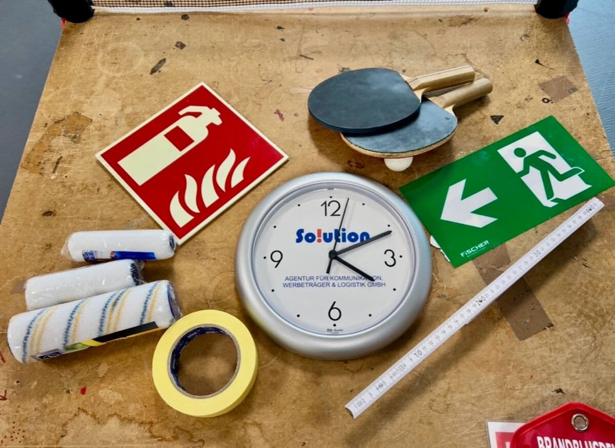 Werkzeug, Farbrollen und Uhr auf einer Werkbank